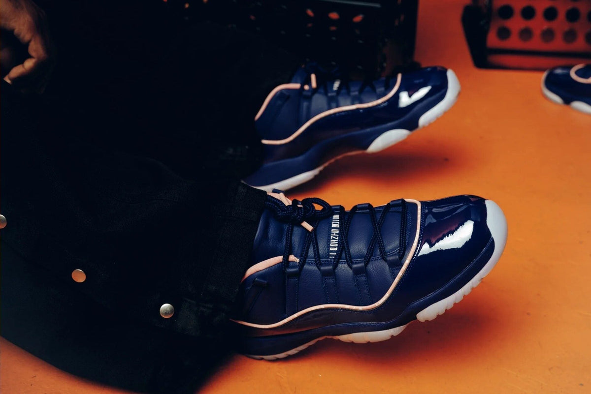 On-foot APB x Air Jordan 11 Low Made For Locals Binary Blue/Rust Pink on orange floor — photo via Nice Kicks