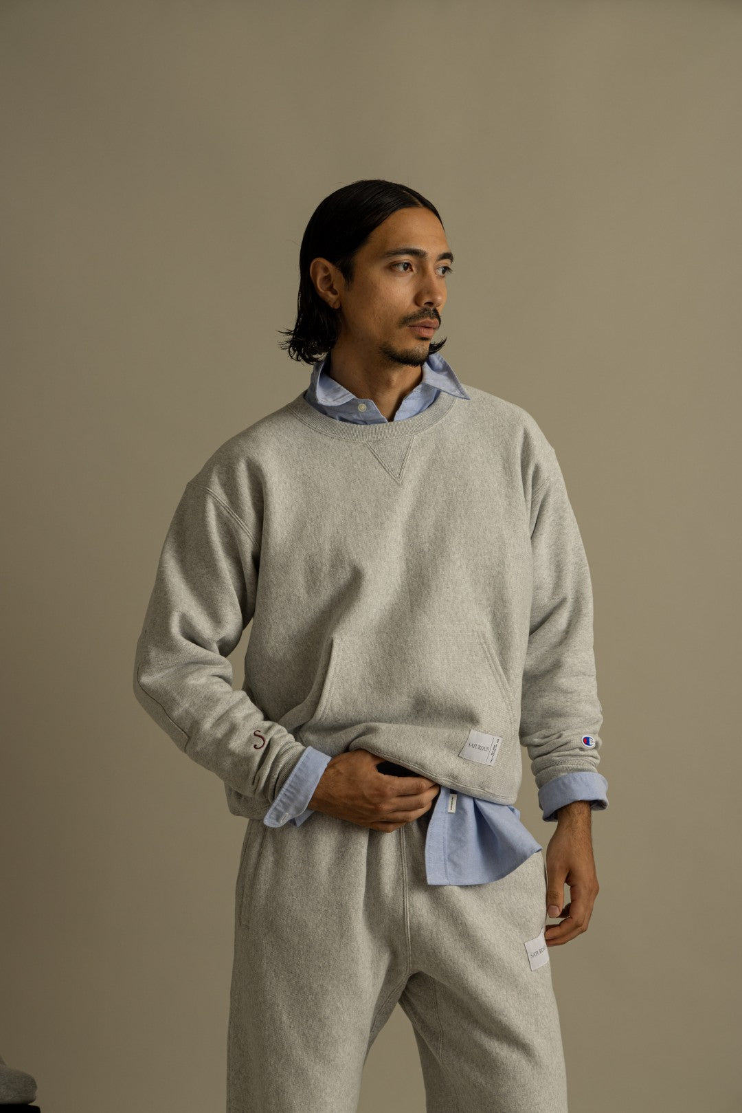 Model in the Champion for Saturdays NYC heather grey crewneck sweatshirt and sweatpants over a blue oxford shirt. Photo via Fullress