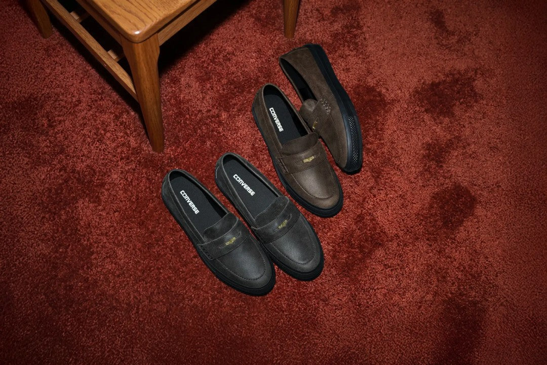 Converse All Star Coinloafer Waxed Leather in Dark Brown and Vintage Black on a red carpet next to a wooden chair. Photo via Fullress