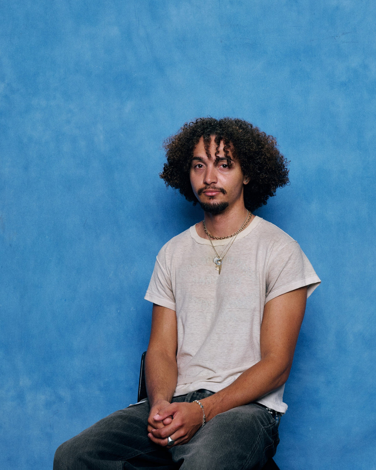 LA designer Masyn seated in front of a blue backdrop, official Nike Air Works portrait