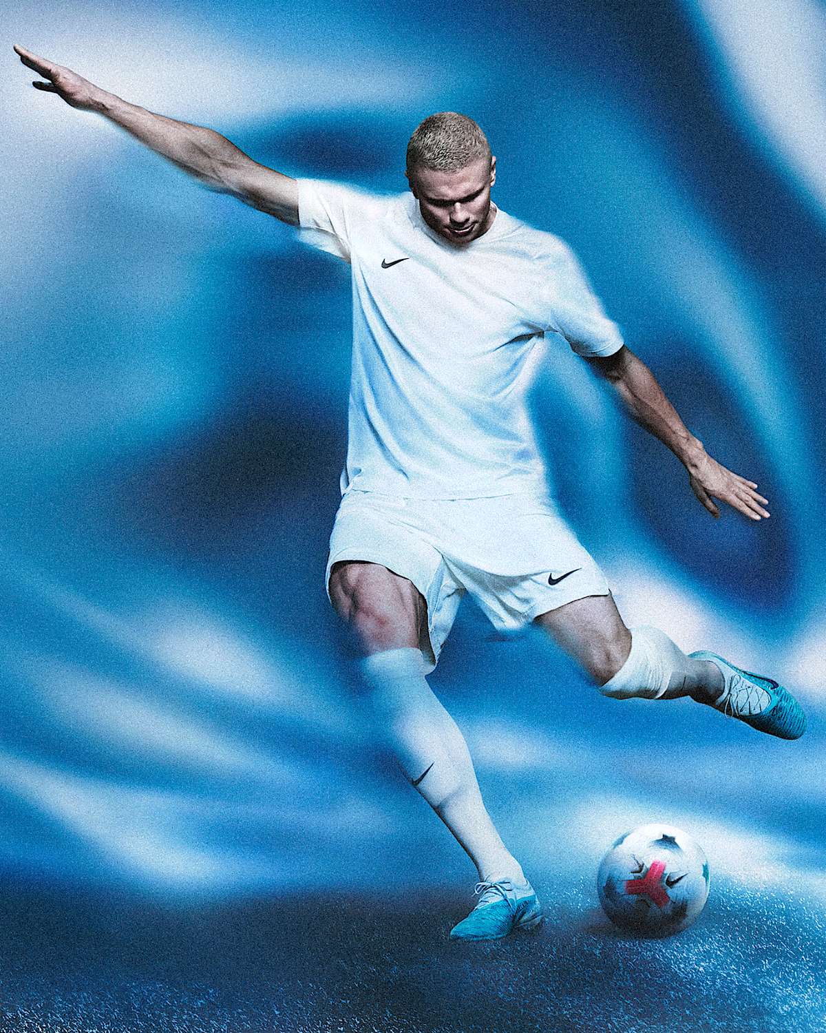 Erling Haaland in white Nike kit striking with Phantom 6 Low Elite Baltic Blue cleats — official Nike campaign