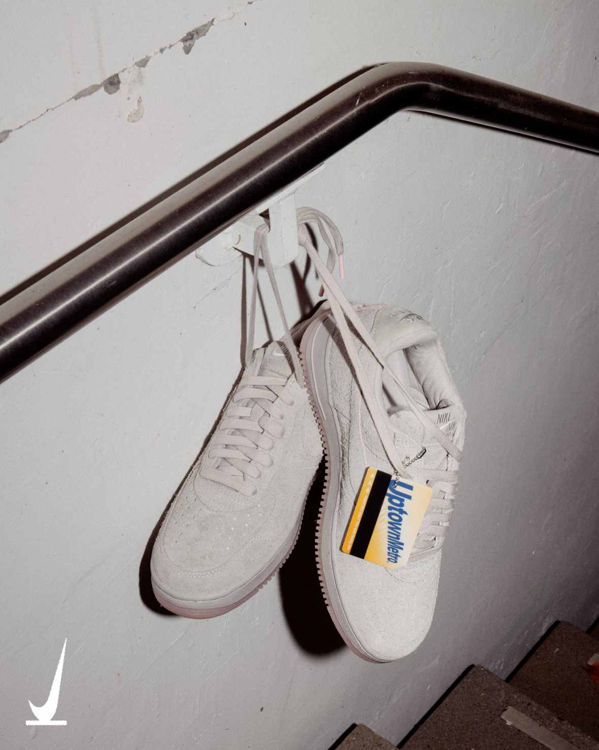 Nike Air Force 1 '01 Subway Rat in College Grey shaggy suede hanging from a subway stairwell rail with its MetroCard-style hangtag — official Nike SNKRS image
