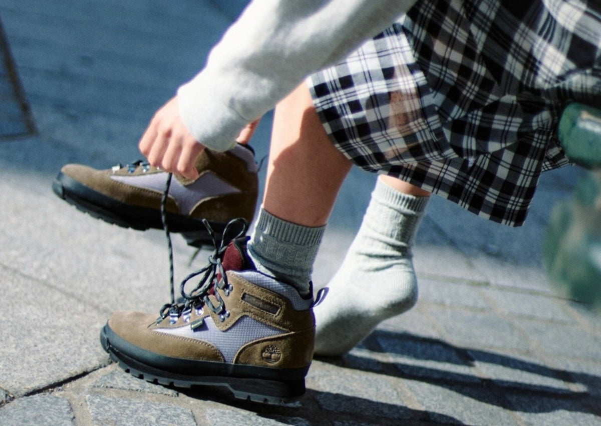 On-foot shot of the Victor Kan x Timberland Euro Hiker GTX in taupe suede with silver mesh and a burgundy tongue on a cobblestone street. Photo via Sole Retriever