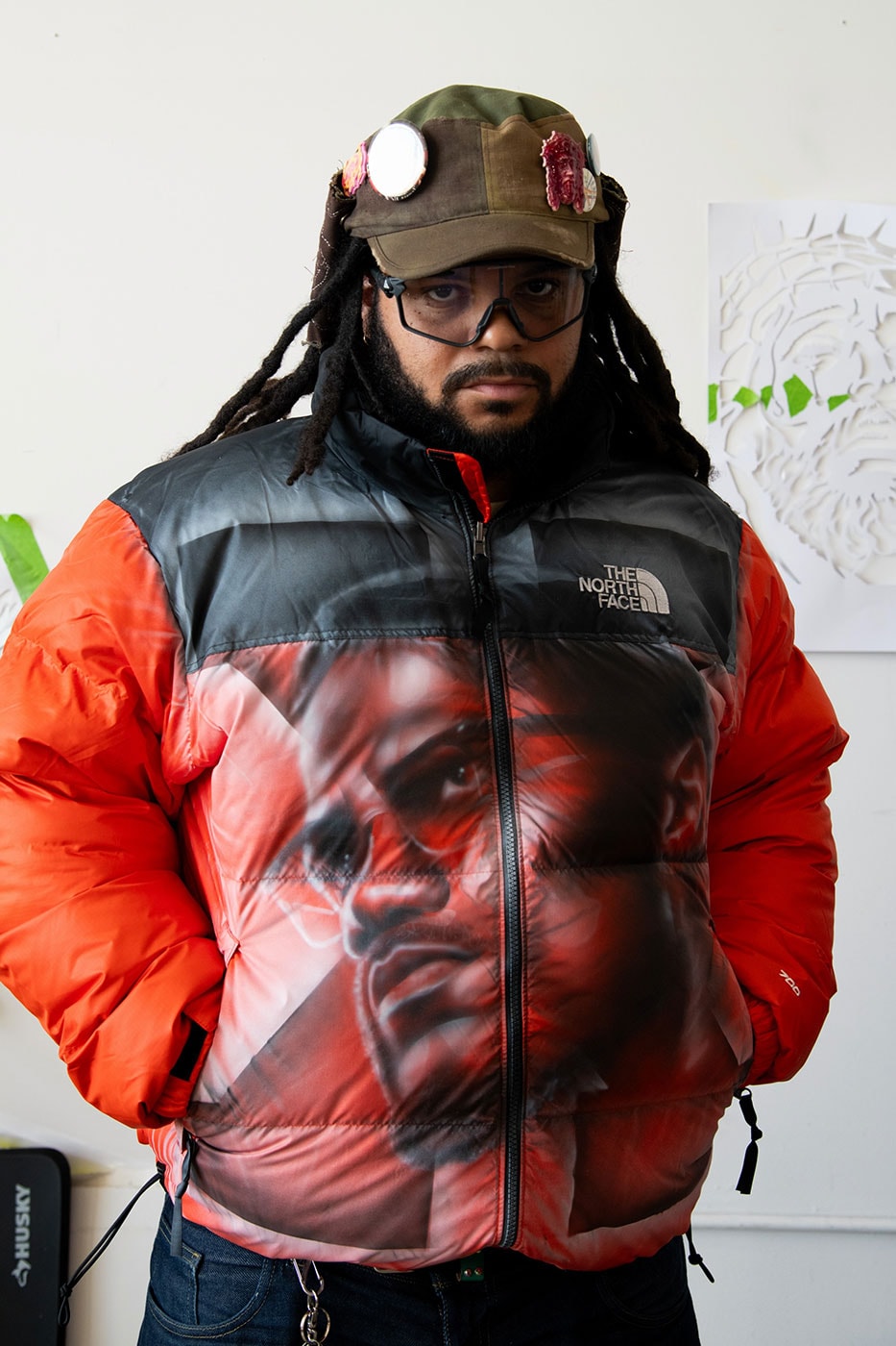 Model wearing an Awake NY x The North Face custom Nuptse with an airbrushed portrait across the black body and orange sleeves. Photo via Hypebeast