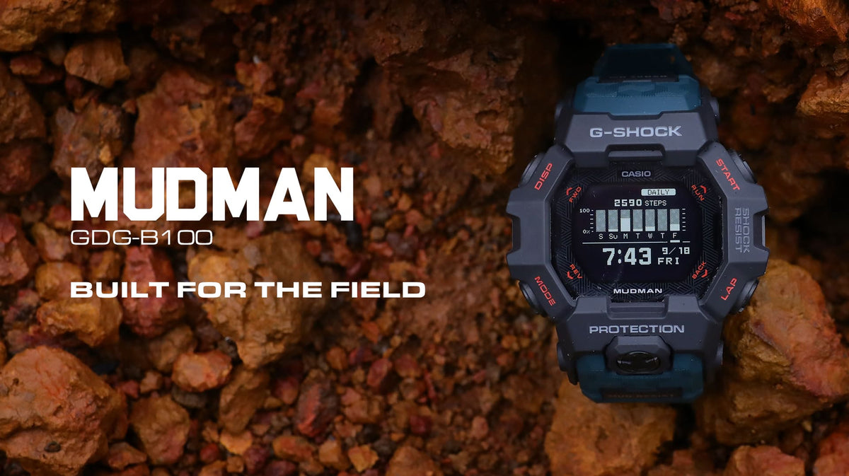 The G-SHOCK MUDMAN GDG-B100 in black and teal sitting in red rock and mud, from Casio's official MUDMAN campaign