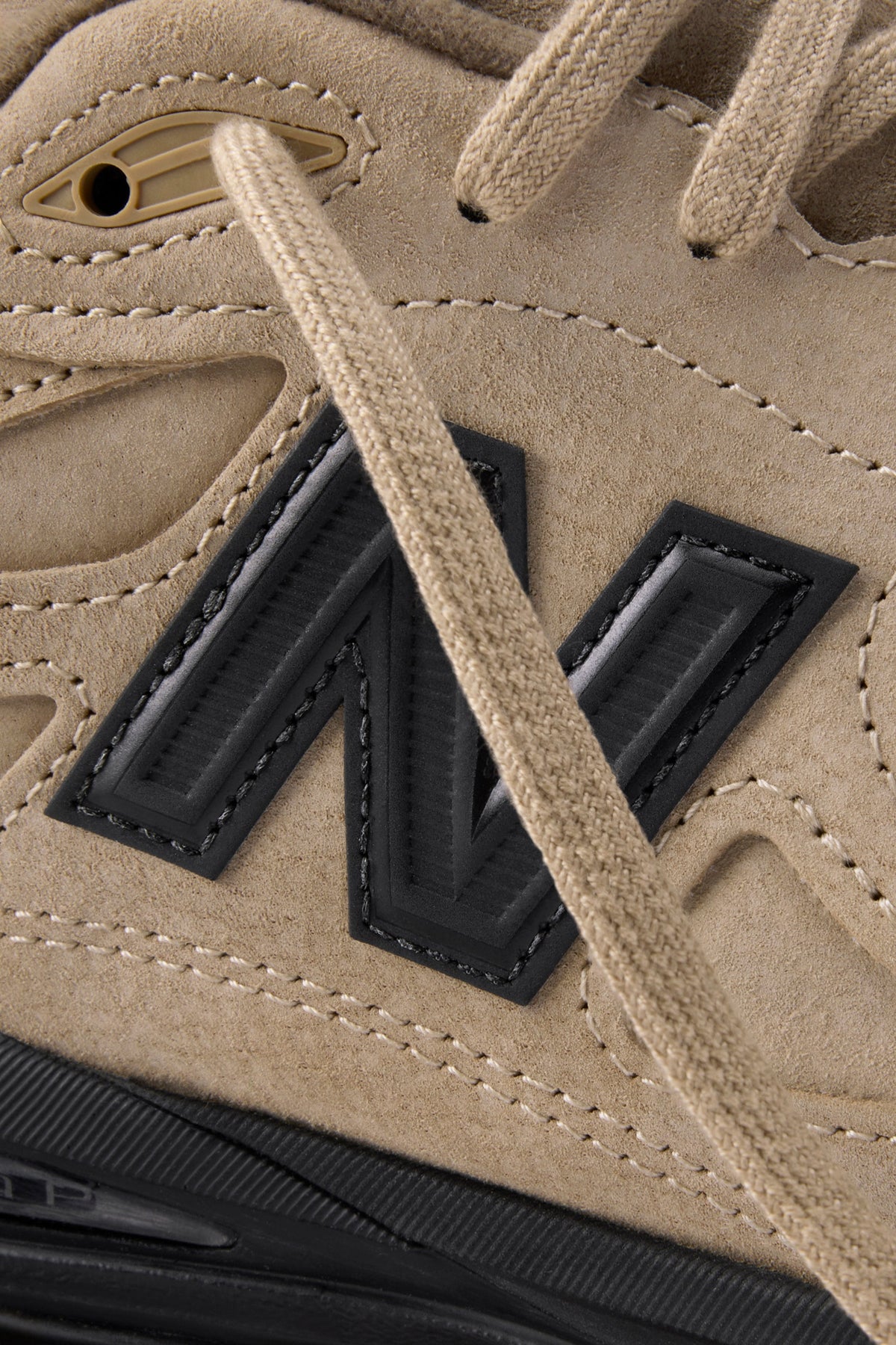 Close-up of the tan suede upper and black N logo on the JJJJound x New Balance 990v3 Suede Made in USA, from JJJJound's official campaign
