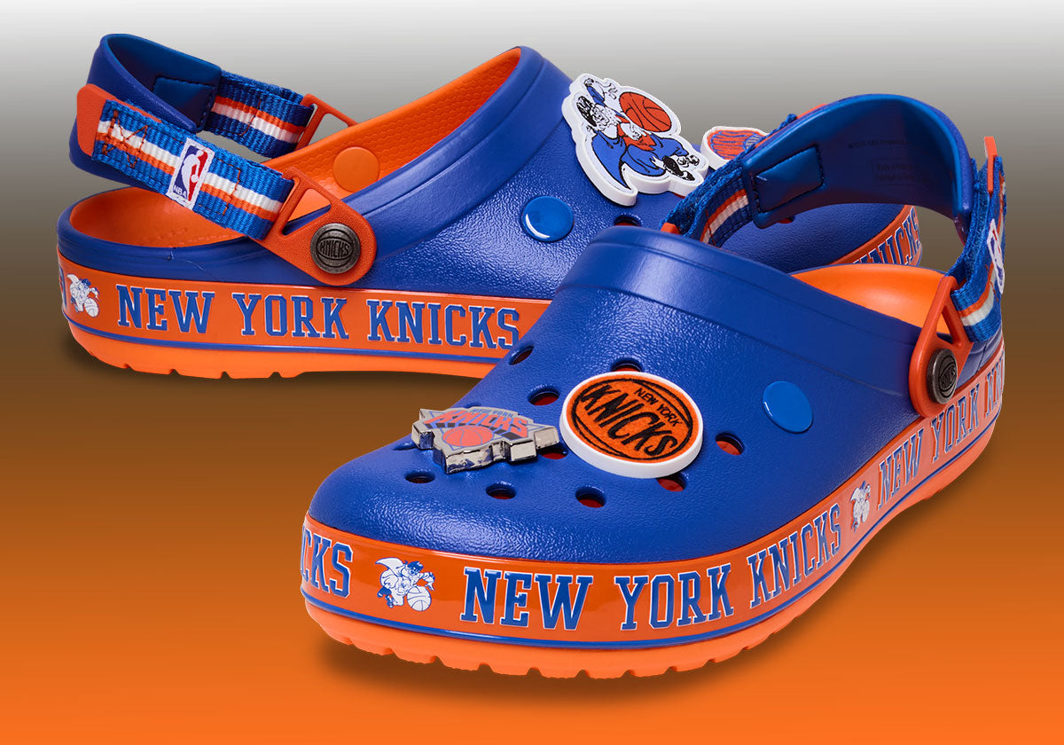 NBA x Crocs Crocband Clog New York Knicks pair on blue-orange team backdrop — Crocs via Sneaker News