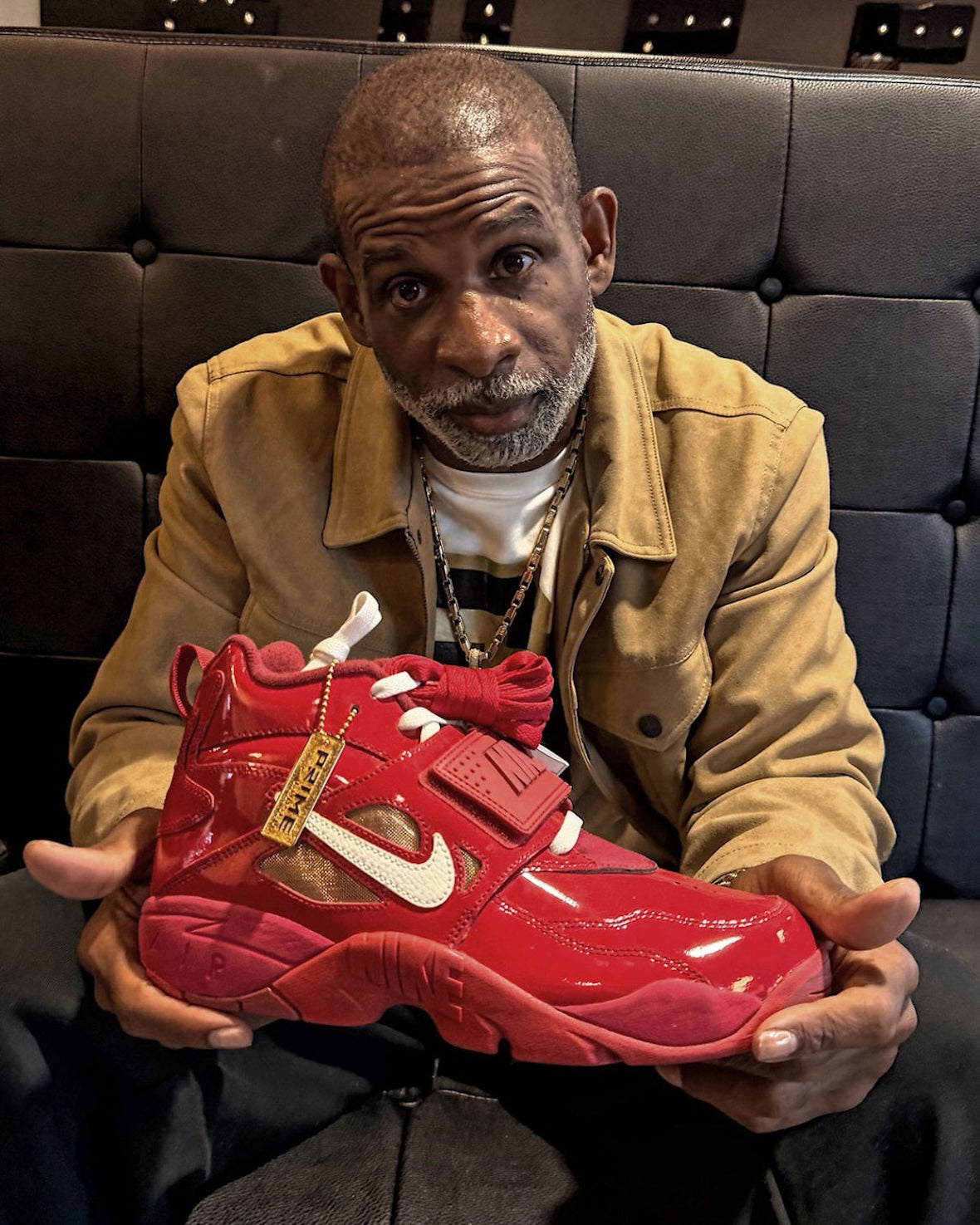 Deion Sanders seated with the Nike Air DT Proto 92 Prime Red JF7592-600 in his hands. Photo: Deion Sanders via Sneaker Bar Detroit