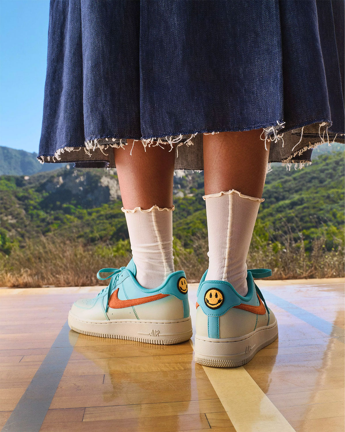 Nike Air Force 1 Low N7 Oasis Teal on foot with smiley-face heel, Holiday 2026 N7 campaign. Official image via Sneaker News