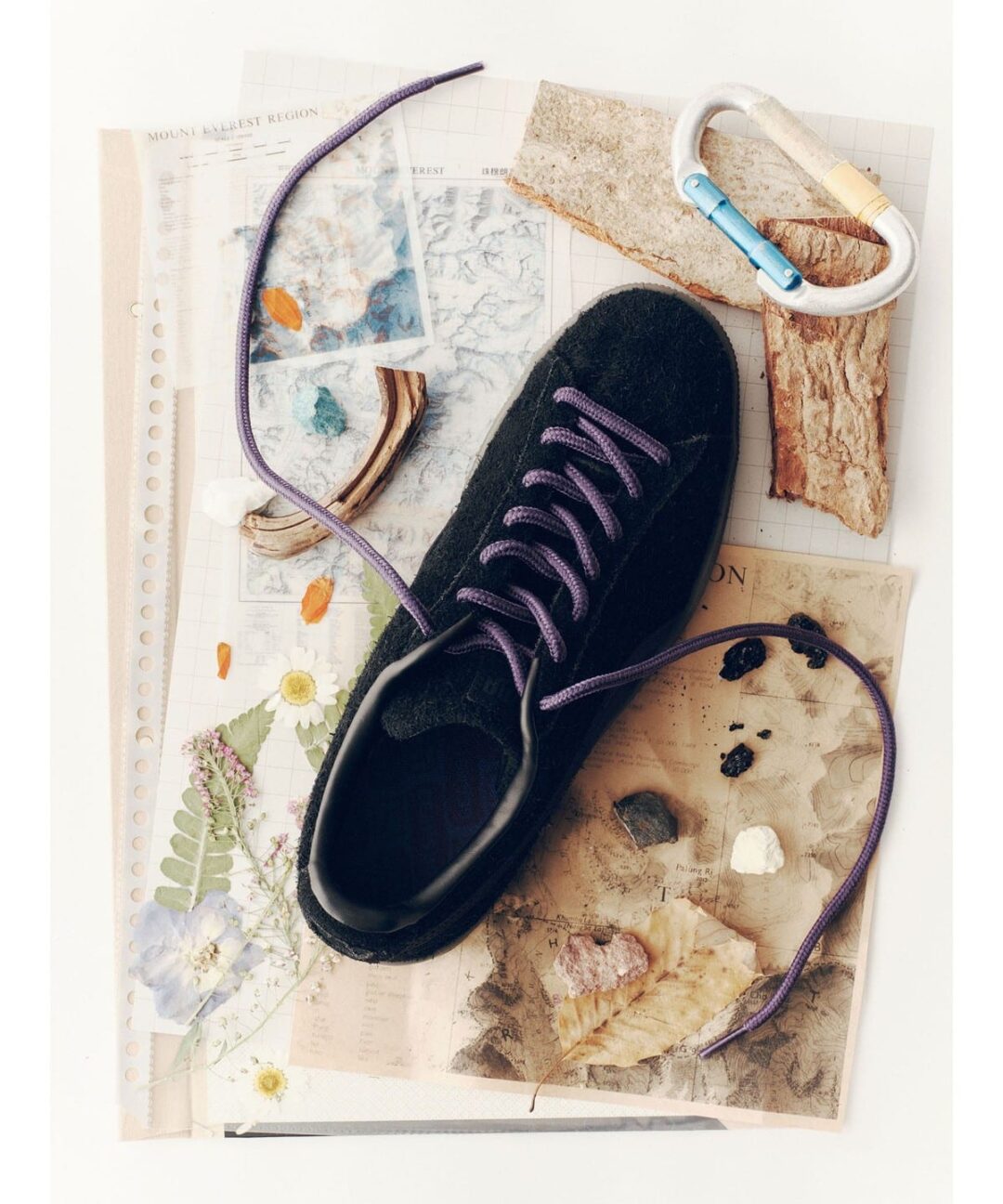 PUMA x BEAMS BOY Suede in black long-hair suede laced with purple laces on a flat-lay of outdoor ephemera. Photo via Fullress