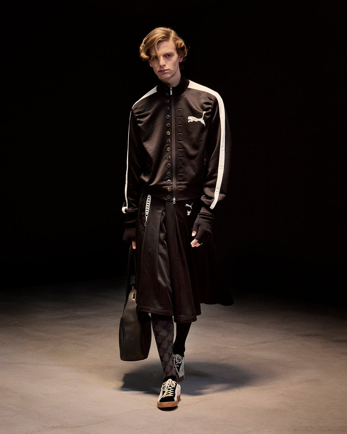 Model in the PUMA × MASU T7 CURIO track jacket with angel monogram socks and PUMA Suede sneakers, MASU Fall/Winter 2026 collection — official MASU image