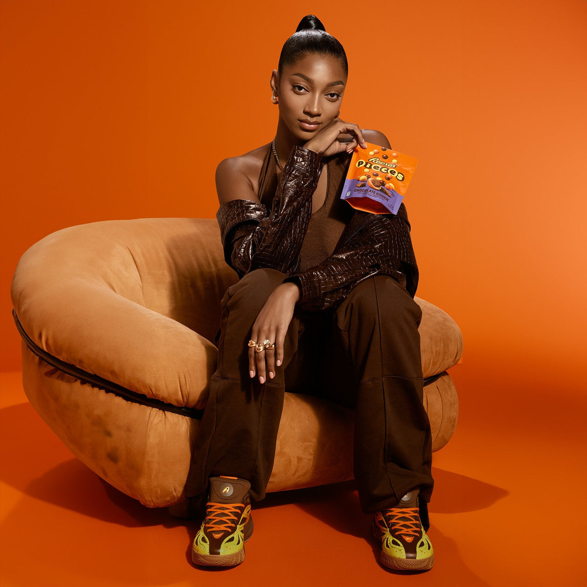 Angel Reese on-model in Reese's × Reebok Angel Reese 1 — orange campaign chair look with Reese's Pieces — official Reebok PDP