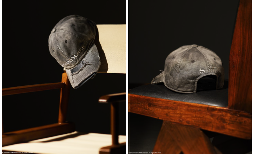 Saint Michael x DreamWorks vintage-washed cap hanging on a director's chair, DreamWorks logo on the front and SAINT on the back. Photo via Fullress