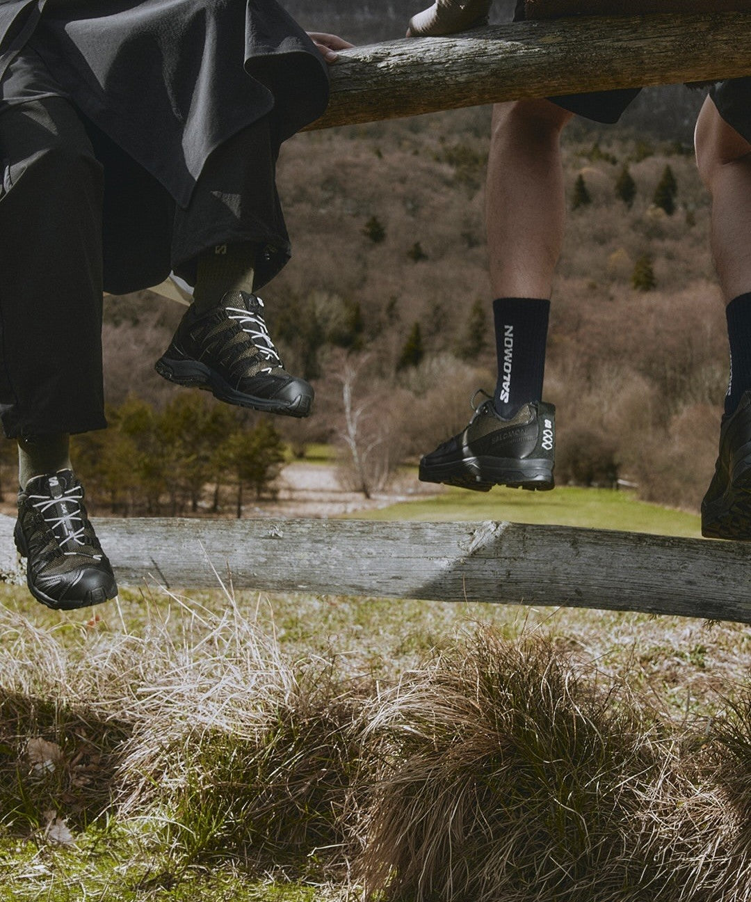 Salomon Alpine Echoes campaign: XA PRO 3D and companion pair on a wooden fence in alpine hills