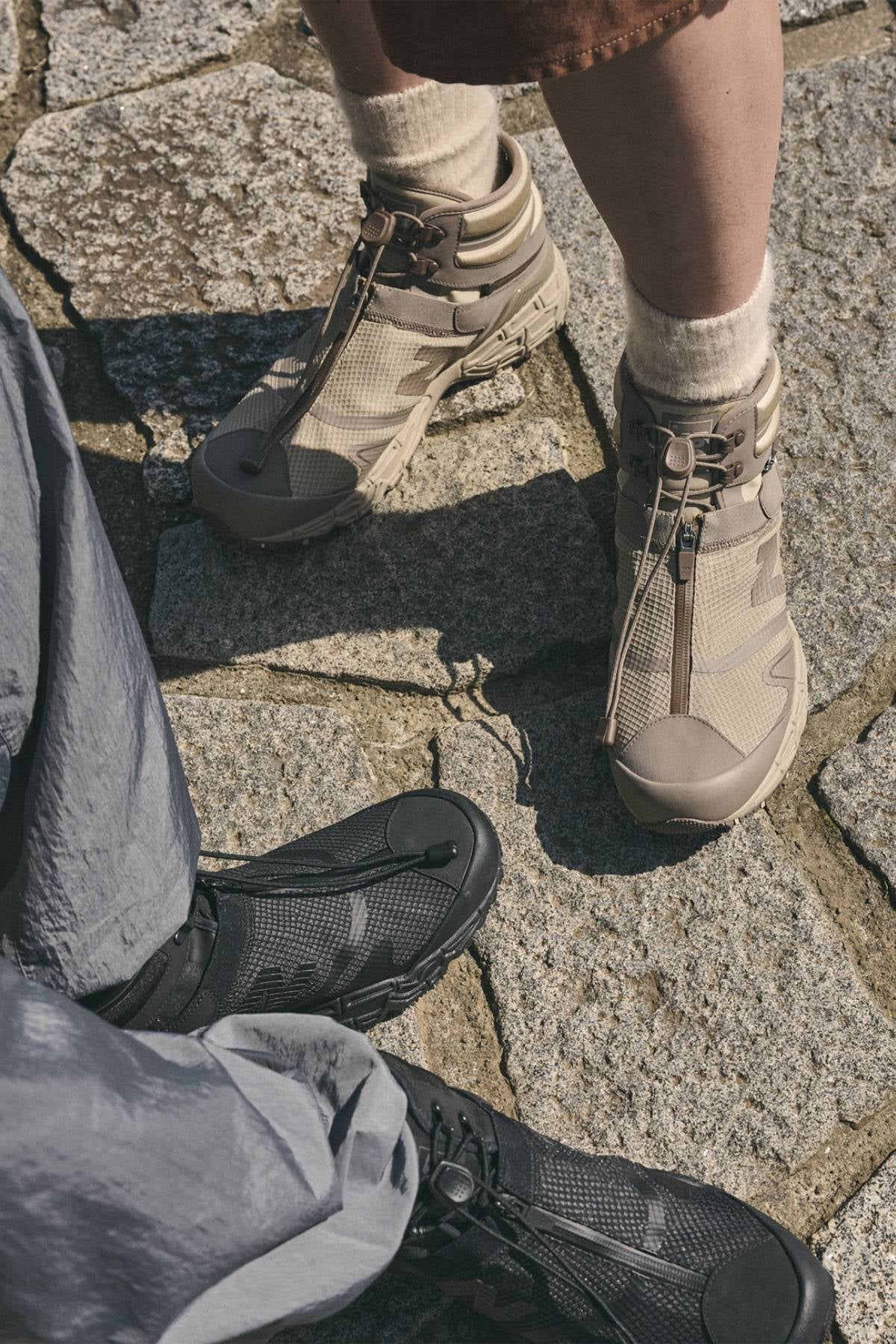 TOKYO DESIGN STUDIO New Balance Niobium Concept 1 on foot in Light Brown and Triple Black on a stone path. Photo: Hypebeast