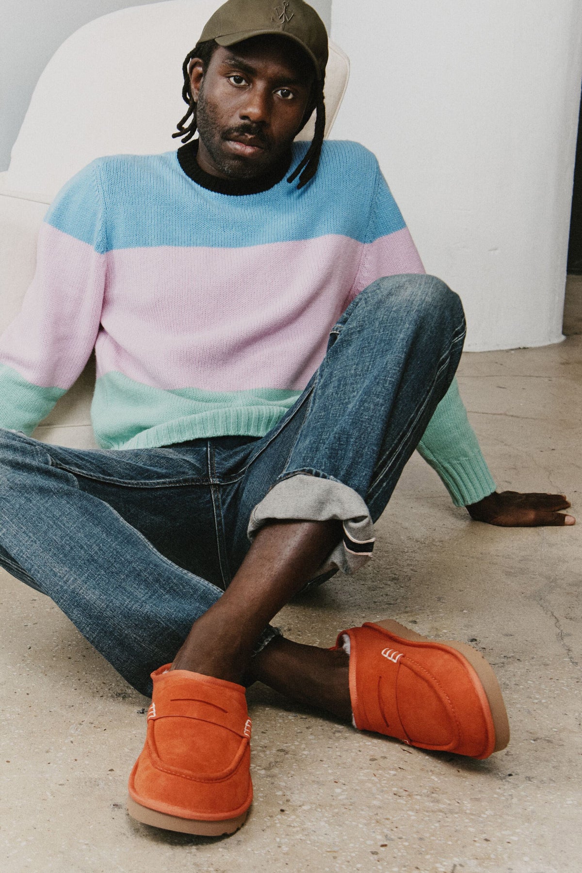 Dev Hynes seated on concrete wearing the UGG x JW Anderson Loafer in Orange — official UGG campaign